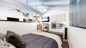 Un dormitorio moderno con una cama grande, un ventilador de techo, un televisor y vistas al exterior.