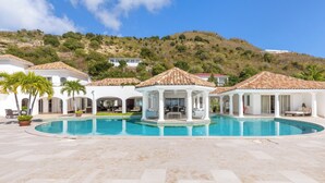 A resort with a large pool, covered seating areas, and a mountainous backdrop. - Villa Petite Plage 4  | Beach Front - Located in  Stunning Grand Case with Private Pool (Grand-Case)