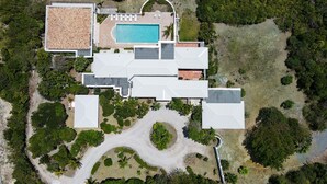 Vue aérienne d’une propriété dotée d’une piscine, d’un patio couvert et d’un jardin aménagé.