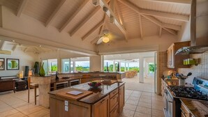 Una cocina amplia con una isla grande, armarios de madera y un techo alto con vigas a la vista.
