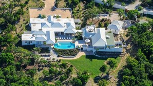 Vista aérea de un resort con varias construcciones, una piscina central y vegetación circundante.