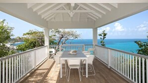 A covered outdoor area with a wooden deck, white railings, and a table with chairs. - Villa Le Caprice | Beach Front - Located in  Tropical Baie Rouge with Private Pool (Lowlands)