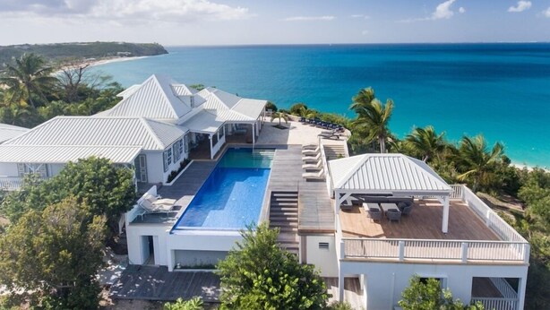 A resort with a large swimming pool, multiple guest rooms, and a view of the ocean. - Villa Le Caprice | Beach Front - Located in  Tropical Baie Rouge with Private Pool (Lowlands)