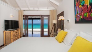 A bedroom with a bed, a television, a lamp, and a painting. - Villa Blue Beach  | Beach Front - Located in  Stunning Baie Longue with Private Pool (Les Terres Basses)