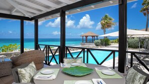 A covered outdoor dining area with a view of the ocean and a pool. - Villa Blue Beach  | Beach Front - Located in  Stunning Baie Longue with Private Pool (Les Terres Basses)
