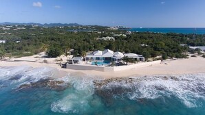 A beachfront property with a pool, surrounded by trees and a view of the ocean.