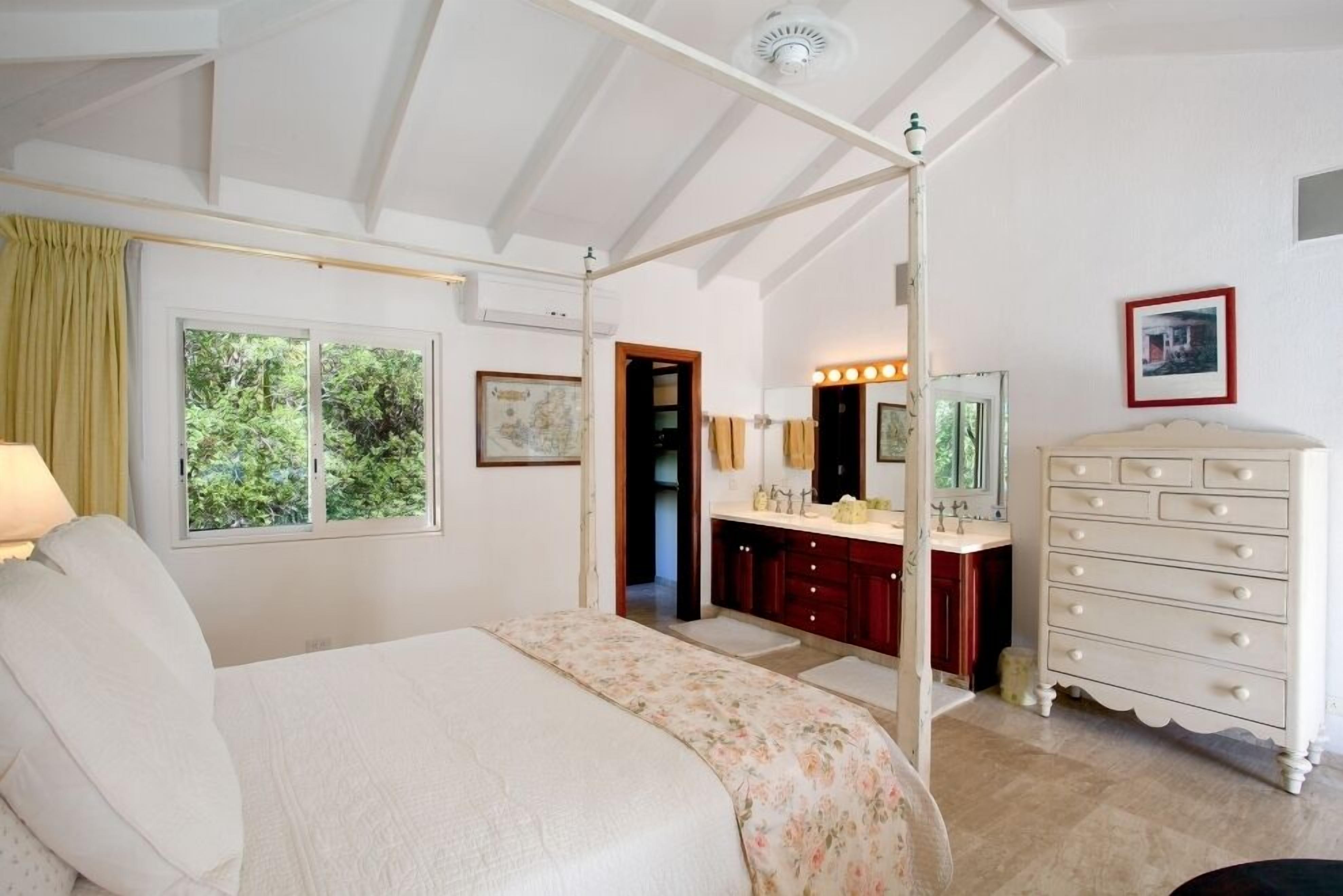 Een slaapkamer met een groot bed, een kaptafel met spiegel en een kledingkast.