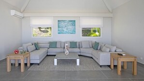 En moderne stue med en grå modulsofa, to træsideborde, et sofabord i midten og billedkunst på væggene.