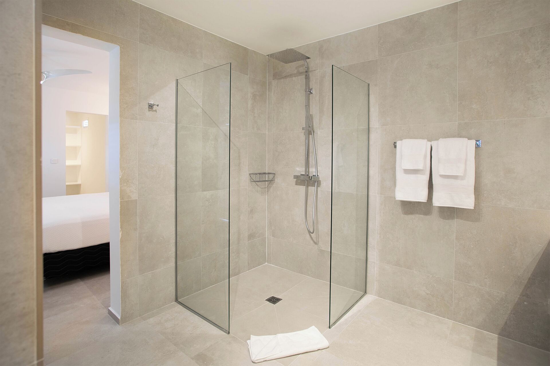 Une salle de bain moderne dotée d’une douche à parois de verre, d’une porte en verre et d’un porte-serviettes avec deux serviettes.