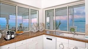 A modern kitchen with large windows, a coffee maker, and a dish rack.