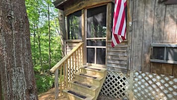 Eine Holzhütte mit Veranda, Treppe und einer amerikanischen Flagge.