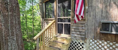 Uma cabana de madeira com varanda, escadas e uma bandeira americana.