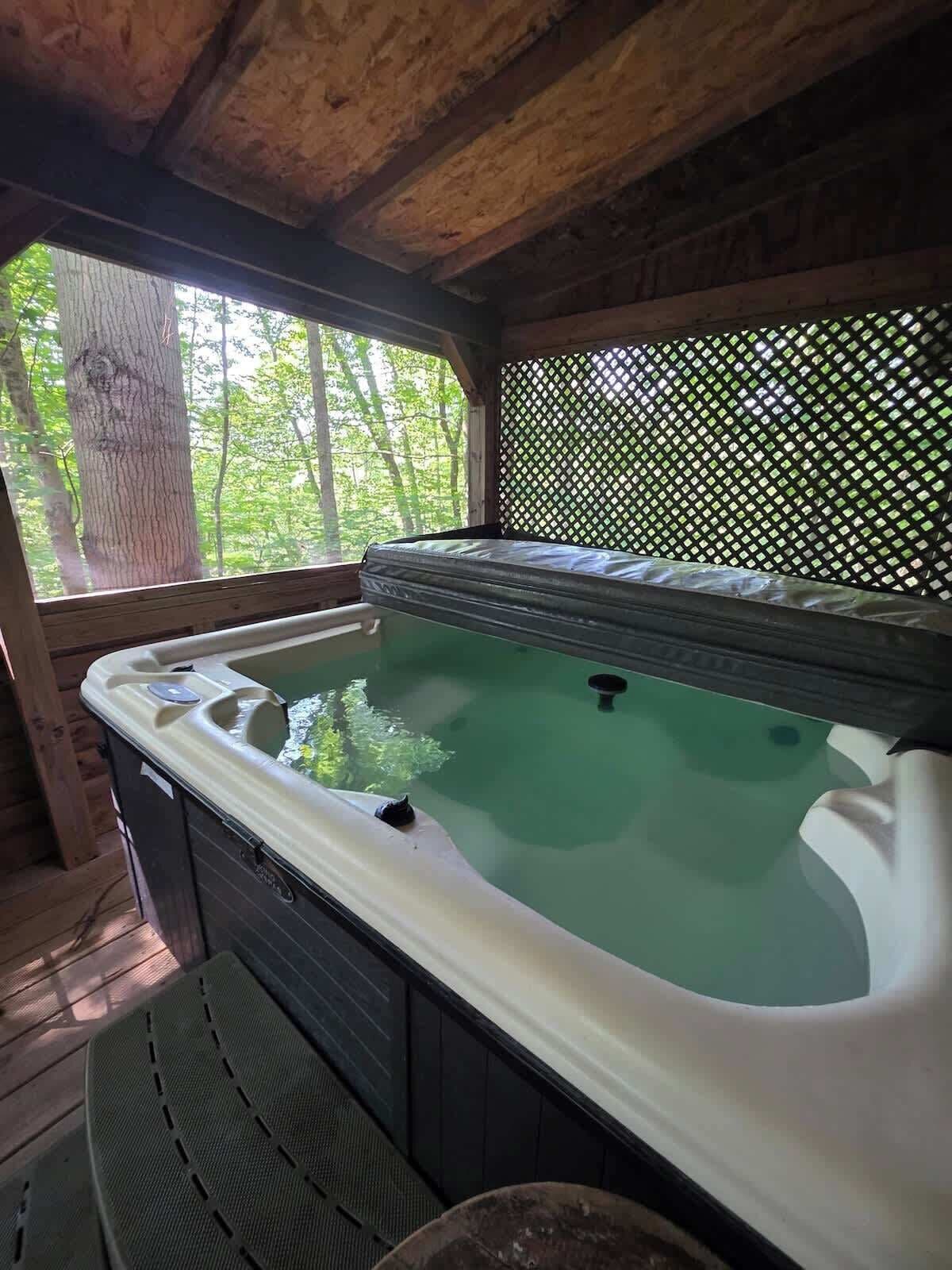 Un bain à remous avec une terrasse en bois et une vue sur les arbres.