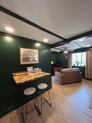A room with a bar area, a sofa, and a painting on the wall. - The Old Moonshiners at Avenwood Cabins (new straitsville)