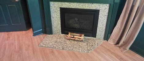 A room with a fireplace, a wooden floor, and a door.