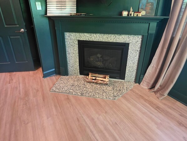 Une pièce avec une cheminée, un plancher en bois et une porte.
