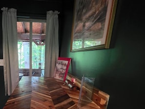 A room with a wooden herringbone floor, a framed poster on the wall, and a window with curtains.