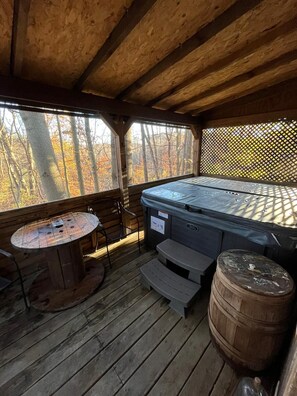 Eine Holzterrasse mit Whirlpool, Tisch und Fass.