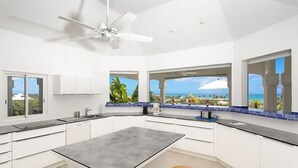 A modern kitchen with a central island, white cabinetry, and large windows offering ocean views. - Villa Oceane  | Ocean View - Located in  Fabulous Terres Basses with Private Pool (Les Terres Basses)