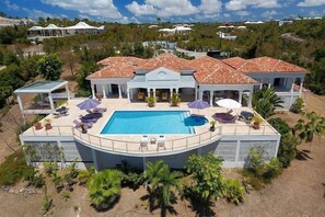 Una casa grande con piscina, varios patios y un jardín ajardinado.