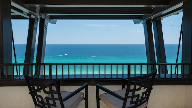 Un balcon avec deux chaises donnant sur l’océan.