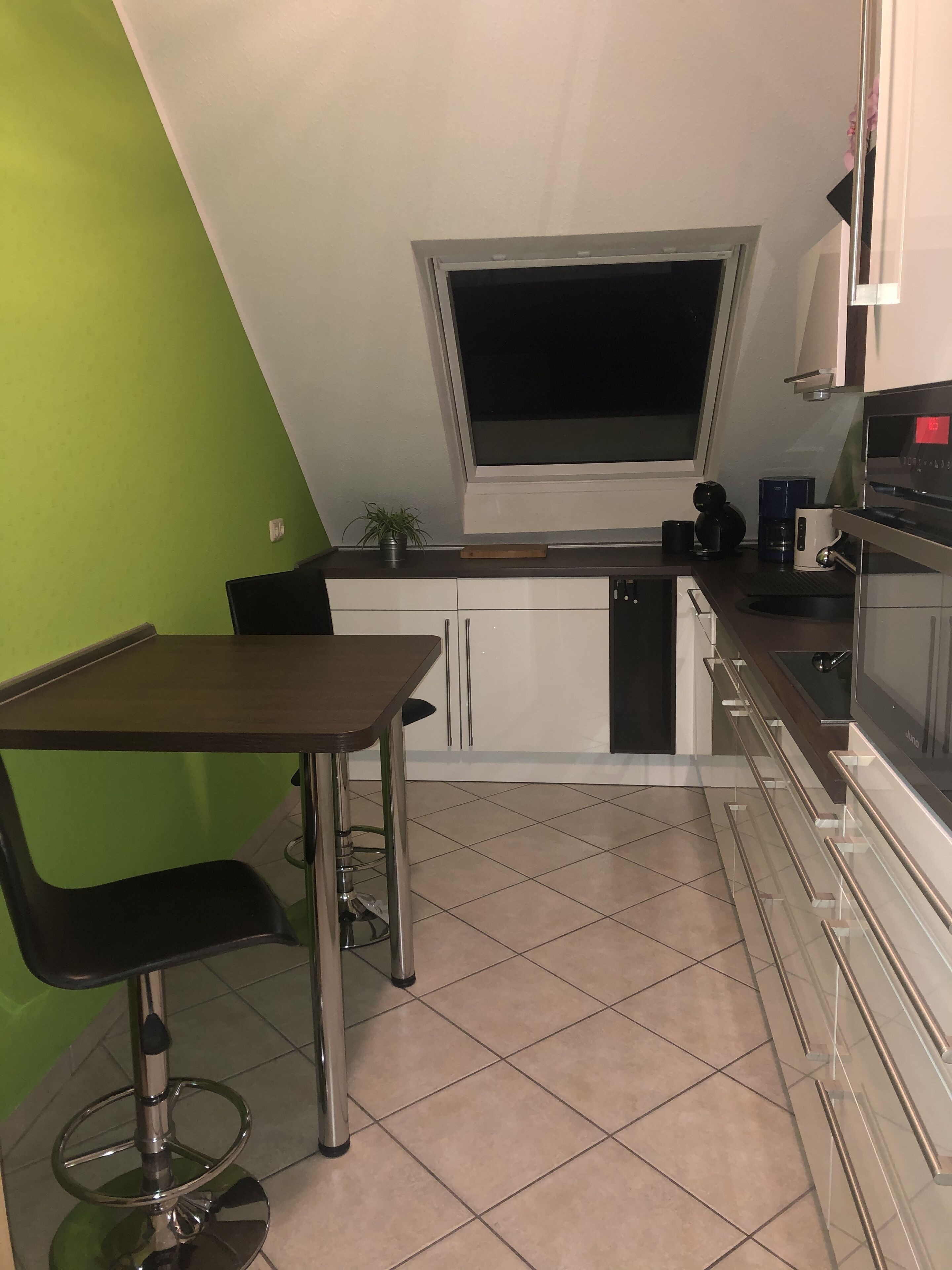 Eine kompakte Küche mit Fenster, Essbereich und eingebautem Backofen.