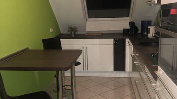 Eine kompakte Küche mit Fenster, Essbereich und eingebautem Backofen.