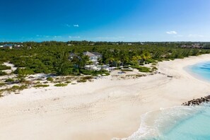A beachside property with a large house, a swimming pool, and lush greenery.