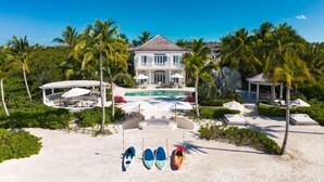 Un'ampia casa con piscina, circondata da palme e da una zona spiaggia con kayak.