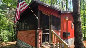 A small cabin with a porch, a flag, and a staircase.