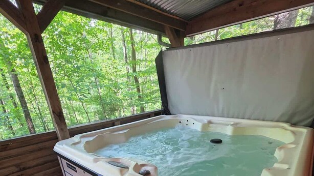 A hot tub with a wooden deck and a covered area.