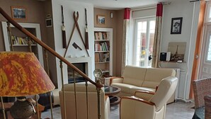 A living room with a staircase, a sofa, a coffee table, and a bookshelf. - Townhouse 12 persons LE DOMAINE DES PAONS 4 ETOILES (Saint-Germain-du-Pert)