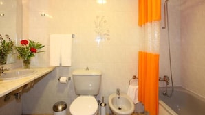 Une salle de bain comprenant des toilettes, un bidet, un lavabo et une baignoire.