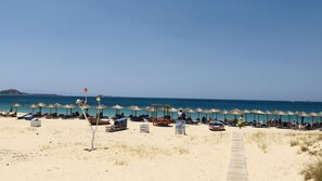 Relax on the beach with comfortable sun loungers and umbrellas, steps from the shore.