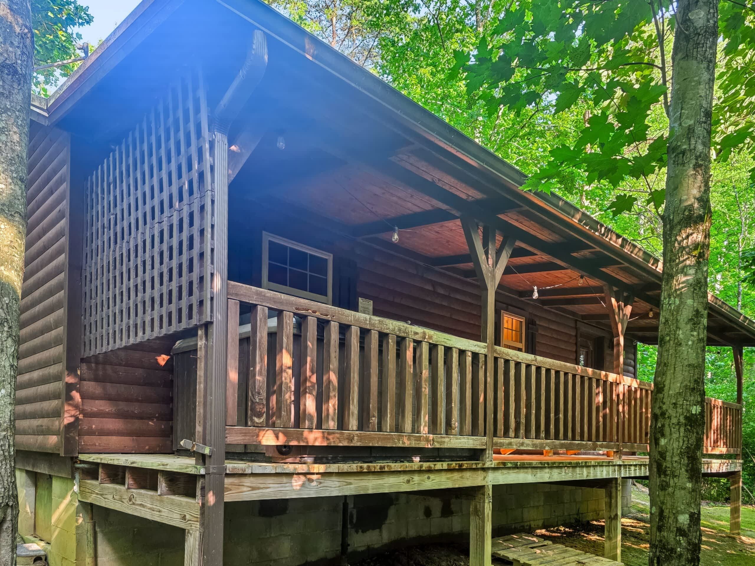 Een houten hut met een veranda, een raam en een deur.