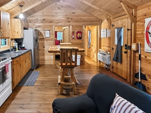 L’intérieur chaleureux d’un chalet comprend une table à manger en bois, un canapé et un coin cuisine équipé d’une cuisinière et d’un évier.