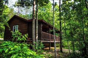 Eine Holzhütte mit Balkon, umgeben von dichtem Wald.