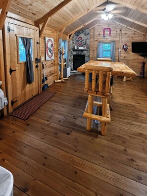 Ein Holzinnenraum mit Kamin, Tisch und Deckenventilator.