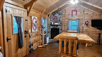 A log cabin interior with a wooden dining table, a fireplace, and a stone wall with an Ohio State logo.