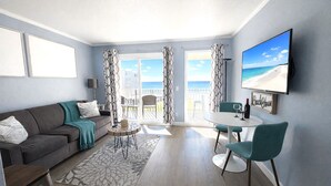 A modern living room with a sofa, coffee table, and chairs, a balcony with a view of the sea, and a flat-screen TV on the wall. - Waterfront, Heated Pool, Balcony, and Serene Views (Tampa)