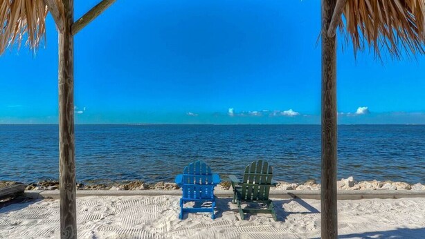 A beach scene with a wooden structure and two chairs facing the ocean. - Waterfront, Heated Pool, Balcony, and Serene Views (Tampa)