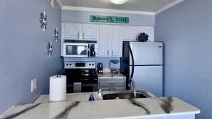 A compact kitchen with white cabinets, a microwave, a stove, a refrigerator, and a sink. - Waterfront, Heated Pool, Balcony, and Serene Views (Tampa)