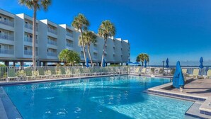 A swimming pool with lounge chairs and umbrellas, surrounded by palm trees and a hotel building. - Waterfront, Heated Pool, Balcony, and Serene Views (Tampa)