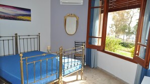 Een slaapkamer met een bed, een raam, een spiegel en een schilderij aan de muur.