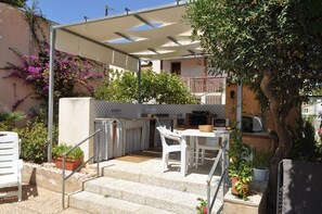 A patio with a table and chairs, a barbecue area, and potted plants. - Villa Faro on the waterfront with a private garden (TRAPANI)