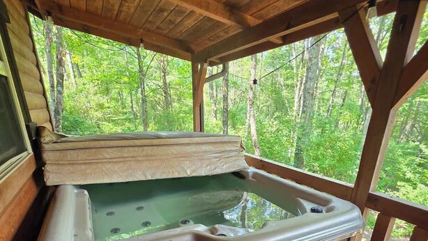 Ein Whirlpool in einer Holzhütte mit Blick auf einen Wald.