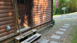 Eine Holzhütte mit Eingangstür, kleiner Veranda und einer Flagge.