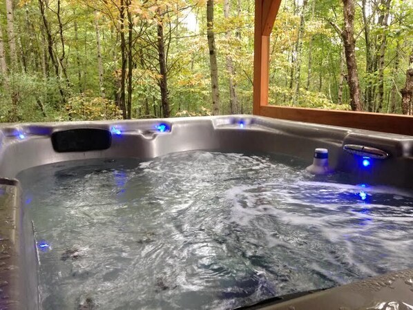 A hot tub with water jets in a forested area.