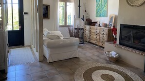 Ein gemütliches Wohnzimmer mit einer Couch, einem Kamin, einer Holzkommode und einem großen Fenster.