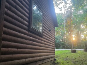 Una cabaña de troncos con ventana y vistas a un bosque.